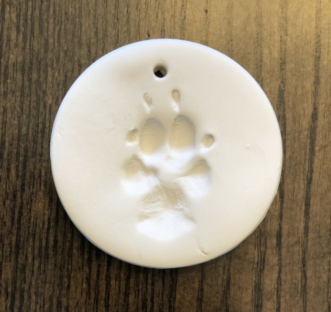A white clay ornament with a dog paw print.
